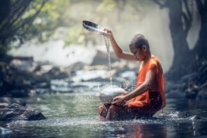 Das Bild zeigt einen jungen Mönch in einem seichten Gewässer sitzend: Taijiquan - Nichts auf der Welt ist weicher als das Wasser, in der Weichheit liegt die Kraft der Stärke, die alles Harte bezwingen kann.